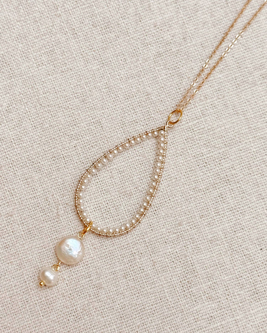 Delicate gold necklace with pearls on a beige fabric background