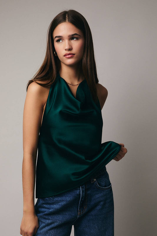 Woman wearing a green sleeveless top and blue jeans against a plain background